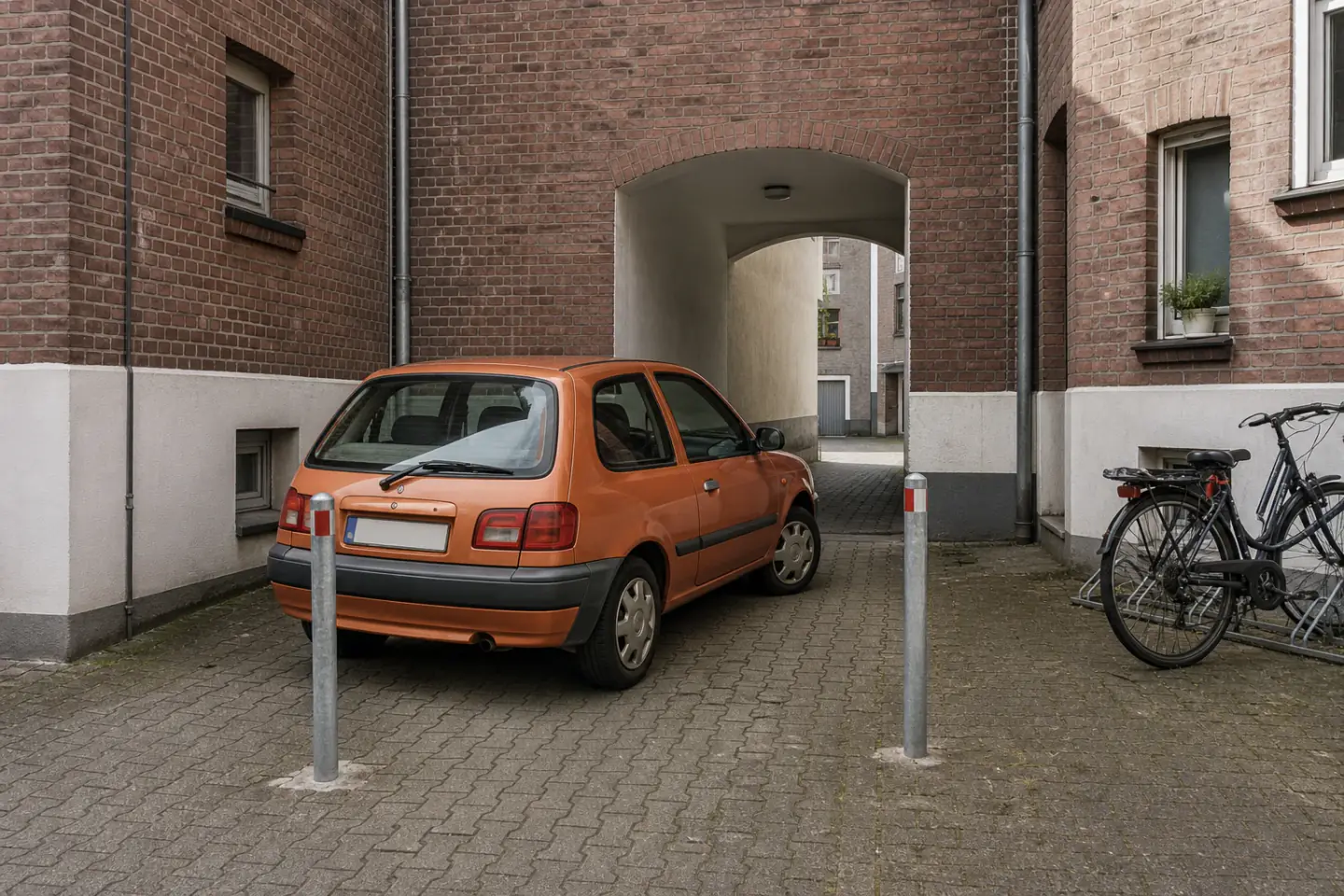 Beispielhafte Verkaufssituation: oranger Kleinwagen zwischen festen Pollern in einem Kamp-Lintforter Innenhof