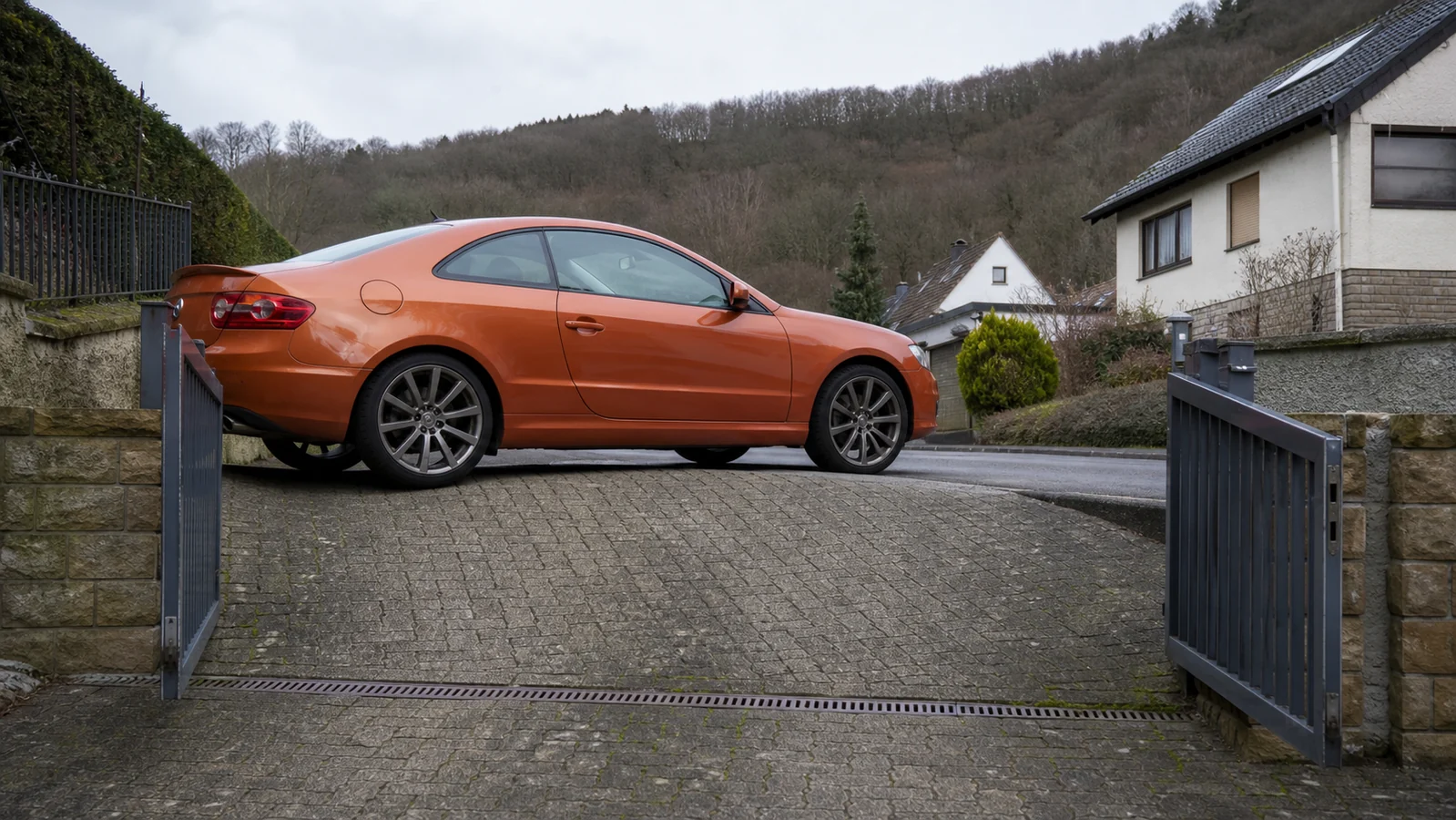 Beispielhafte Verkaufssituation: oranges Coupé auf einer scharfen Rampenkuppe zwischen Grundstück und Straße in Wetter-Volmarstein